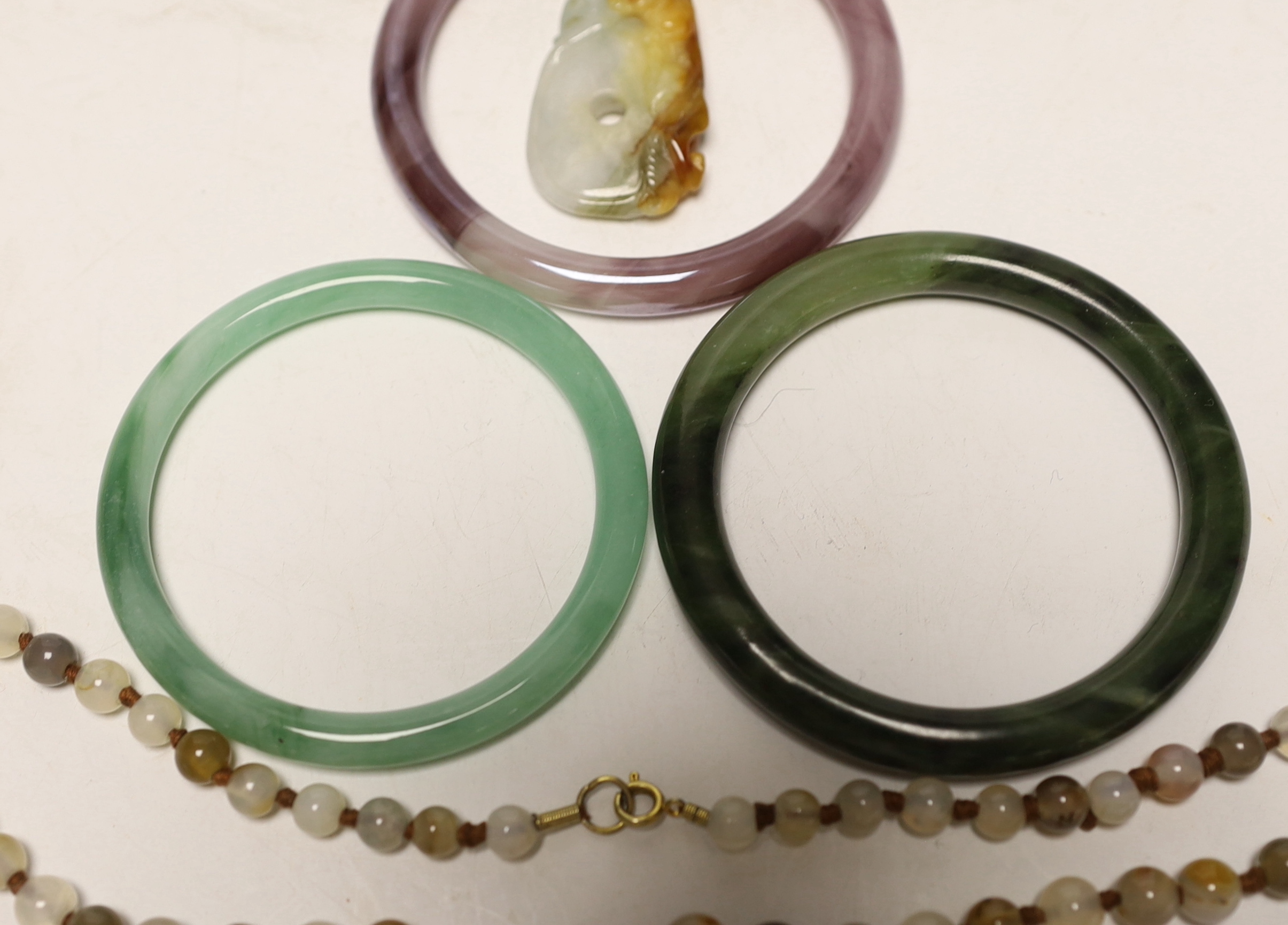 Two Chinese jade bangles, another, a jade pendant and beads